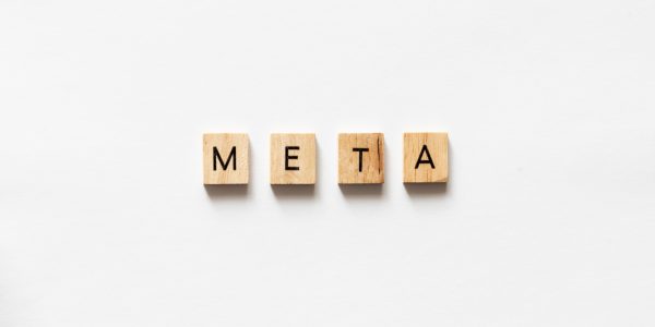 META spelled out with wooden letter tiles on white surface.