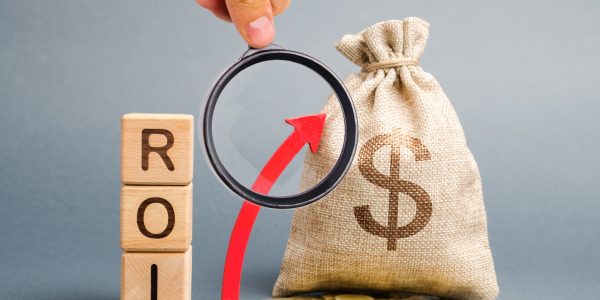 Wooden blocks with the word ROI and the up arrow with the money bag